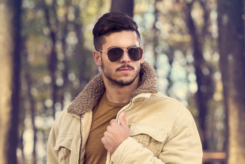Stylish man with sunglasses posing in autumn park